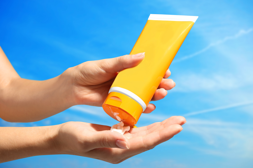 Hands squeezing sunscreen bottle