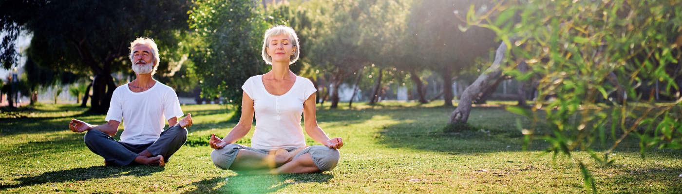 An older couple meditates in a park. Geriatric Orthopedic Care Leads to Lives Led Best.